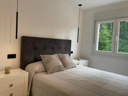 a white bedroom with a bed and a window at Apartamentos Toffe in Outes
