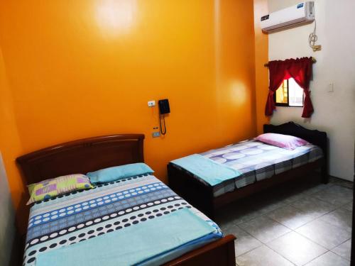 2 camas en una habitación con paredes de color naranja en Hotel Boston en Guayaquil