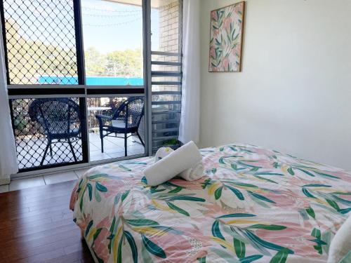 a laptop on a bed in a bedroom with a balcony at Passage Breeze! in Bongaree