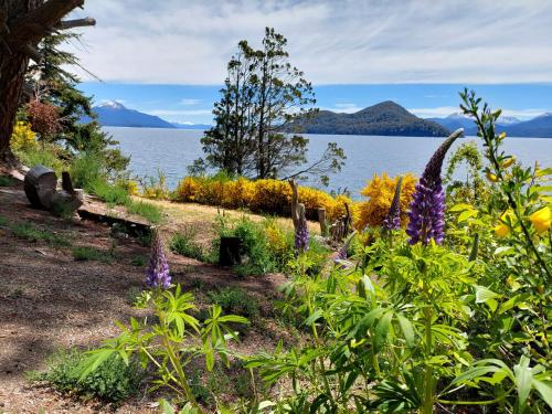 a garden with purple flowers next to a body of water at Eco Cabañas Fardos del Bosque in San Carlos de Bariloche