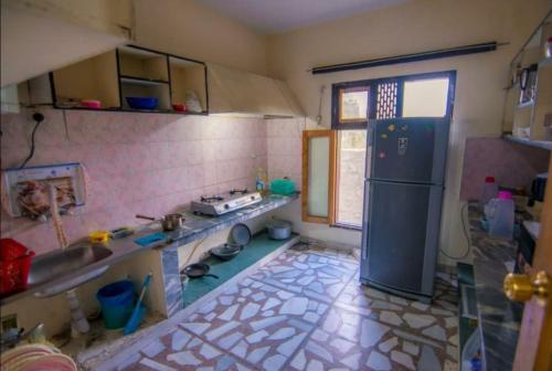 a kitchen with a refrigerator and a tile floor at Al Amin Guest House - Home away from Home in Skardu