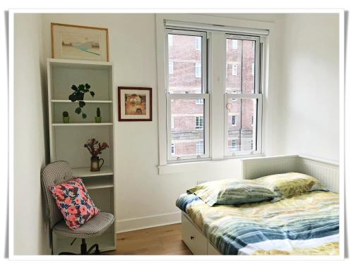 a bedroom with a bed and a chair and windows at Spacious and modern 2 bedroom flat near the City Centre in Edinburgh