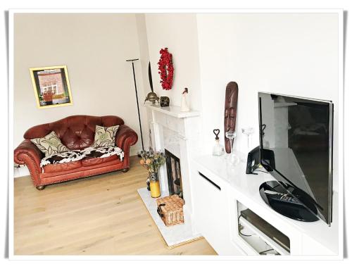 a living room with a couch and a television at Spacious and modern 2 bedroom flat near the City Centre in Edinburgh