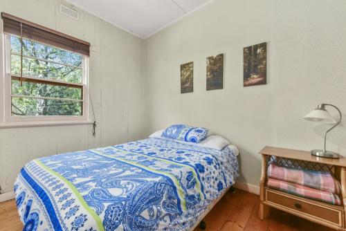 a bedroom with a blue and white bed and a window at Willowhaven in Apollo Bay