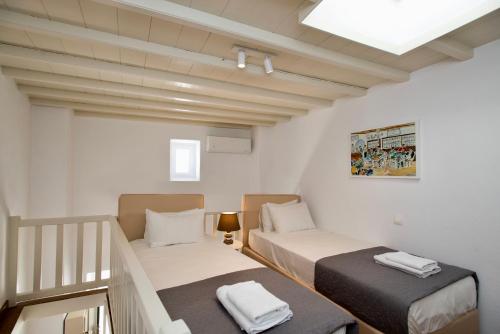 a small room with two beds and a staircase at Myconian Old Town Maisonette THE MIMIs PLACE in Mikonos