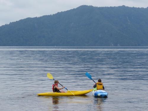 羅托魯阿的住宿－Lake Rotoiti Lakehouse Retreat，两人在大片水中划皮艇