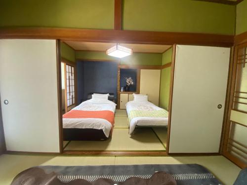 una camera da letto con due letti e uno specchio di 鉄道と山の見える家 a Yufu