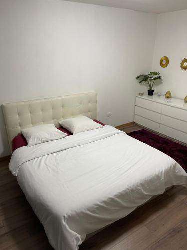 1 cama blanca grande en un dormitorio blanco con una planta en La maison jacuzzi - Privatiser une soirée jacuzzi, en Mandres-les-Roses