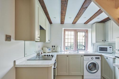 a kitchen with white cabinets and a washer at Redwood Cottage in Nantwich