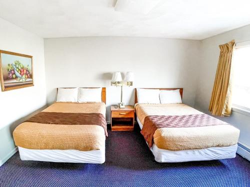 um quarto de hotel com duas camas e uma janela em Utica Rest Inn em Utica