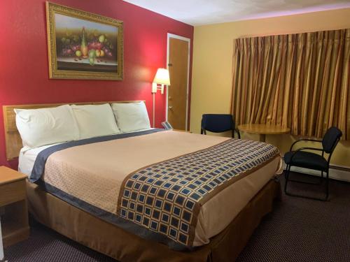Utica Rest Inn في أوتيكا: غرفة فندق بسرير وجدار احمر