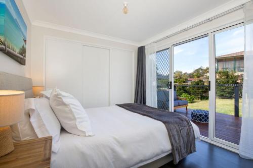 a bedroom with a bed and a large window at WindanSea Cottage Pet Friendly Ocean Glimpses in Vincentia