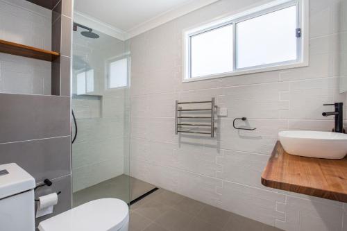 a bathroom with a sink and a toilet and a window at WindanSea Cottage Pet Friendly Ocean Glimpses in Vincentia