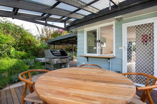 a wooden table and chairs on a patio with a grill at WindanSea Cottage Pet Friendly Ocean Glimpses in Vincentia