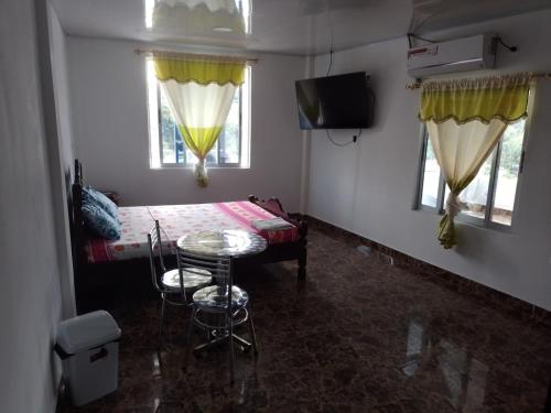 Zimmer mit einem Bett, einem Tisch und 2 Fenstern in der Unterkunft Hostal Apartamentos Delgado in Florencia