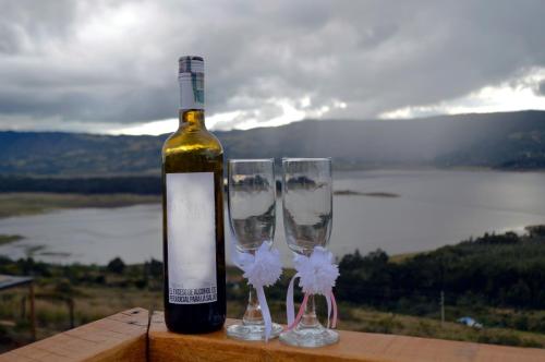 a bottle of wine next to three wine glasses at Glamping Wayra in Guatavita