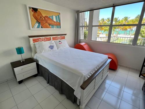 1 dormitorio con 1 cama grande y 2 sillas rojas en Hobie Oceanfront apartment at Isla Verde, en San Juan