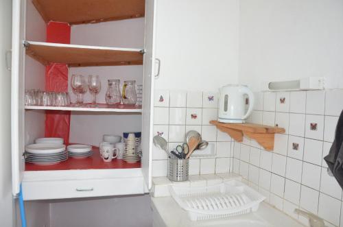 una cocina con platos y vasos en un estante en AU BORD DE L'EAU appartement 50 M2, en Chambon-sur-Voueize