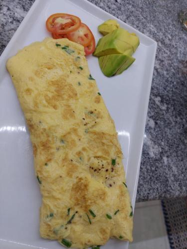 a piece of omelet on a white plate with vegetables at Matteo's hus VILLA RENTAL in Zamboanguita
