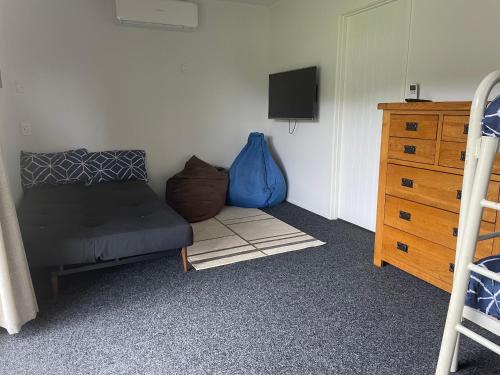 a bedroom with a bed and a tv and a dresser at On The Green - Pauanui Holiday Home in Pauanui