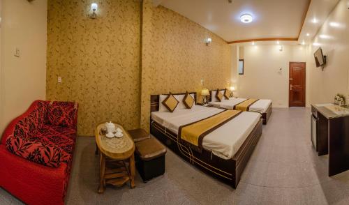 a hotel room with two beds and a chair at Dong Bao Hotel in Chau Doc