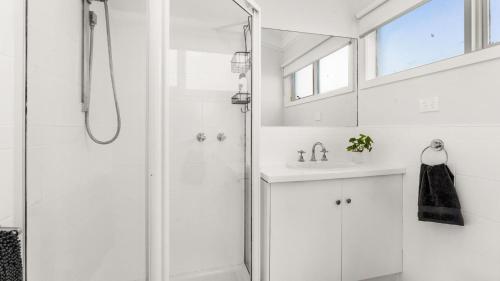 a white bathroom with a shower and a sink at Finding Remo in San Remo