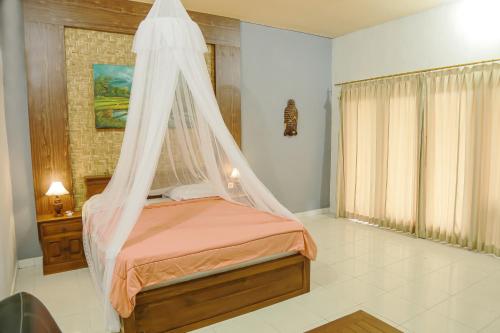 a bedroom with a bed with a mosquito net at Orange Balangan Bungalow in Uluwatu
