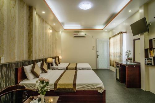 a hotel room with two beds and a television at Dong Bao Hotel in Chau Doc