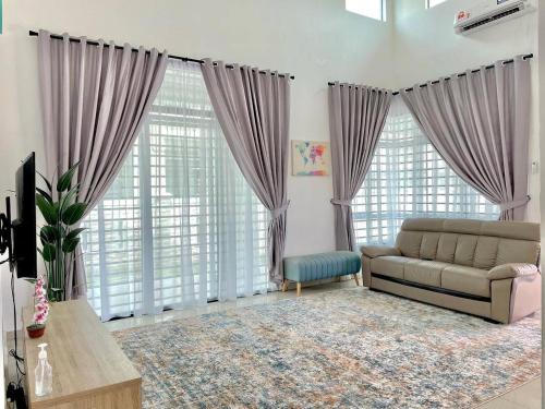 Una sala de estar con un sofá y grandes ventanales. en Syifa Homestay Melaka, en Melaka
