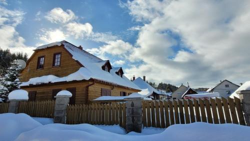 a wooden house covered in snow with a fence at Holidayhouse Chalupa Alžbetka in Važec