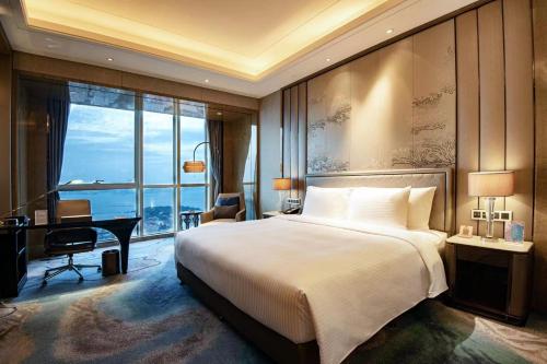 a hotel room with a bed and a desk and a window at Pullman Yantai Center in Yantai