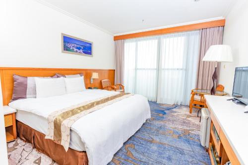 ein Hotelzimmer mit einem großen Bett und einem TV in der Unterkunft Yaling Hotel in Magong