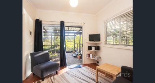 a living room with a chair and a sliding glass door at 27 Rows on Hermitage in Pokolbin