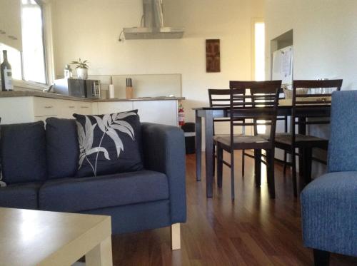a living room with a blue couch and a table at 27 Rows on Hermitage in Pokolbin