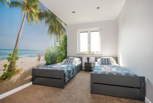 two beds in a room with a mural of a beach at Apartamenty Tęczowe in Darłówko