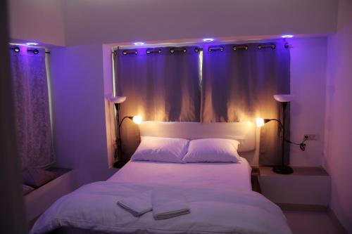 1 dormitorio con cama blanca con iluminación morada en במיוחד בשבילך צימר ערד, en Arad