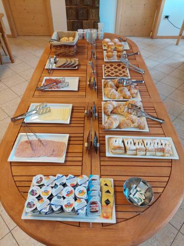 uma longa mesa de madeira com diferentes tipos de pastelaria em Taxus Hostel em Pieve Tesino