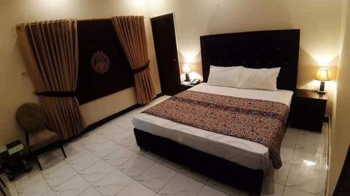 a bedroom with a large bed and two lamps at Hotel Royal Defence in Lahore