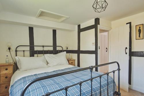 a bedroom with a bed with a blue and white blanket at Lakeside Cottage in Nantwich