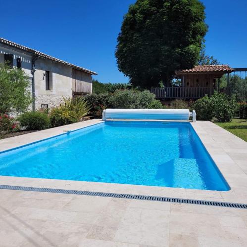 une piscine avec de l'eau bleue dans une cour dans l'établissement Albizia rouge - Gîte de charme à la campagne, à Galgon