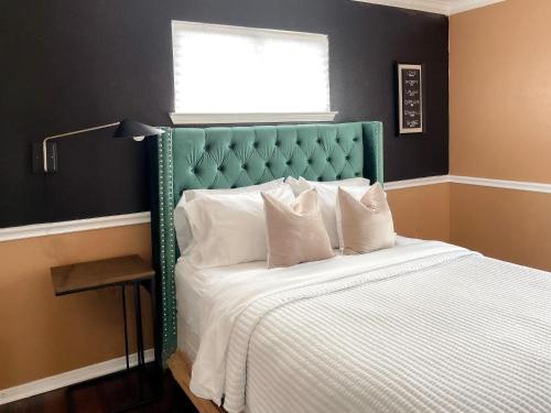 a bedroom with a bed with a green headboard and a window at Modern Chic Home in Channelview