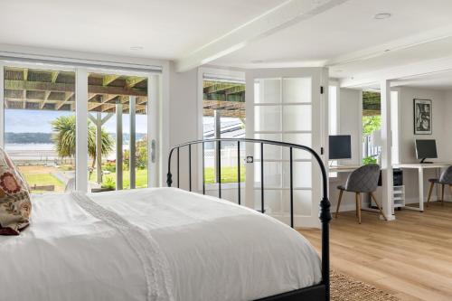 een witte slaapkamer met een bed, een bureau en ramen bij The Sunlight Beach Escape in Clinton