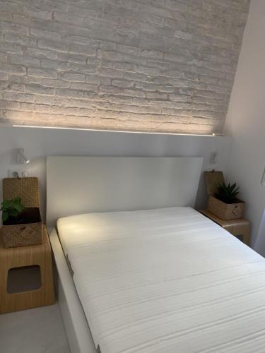 a white bed in a room with a brick wall at Corfudodici in Corfu Town