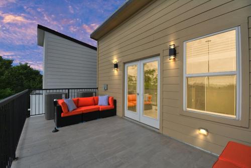 a patio with a red couch on a balcony at La Casa Blanca-Rooftop Skyline with Gameroom in Houston
