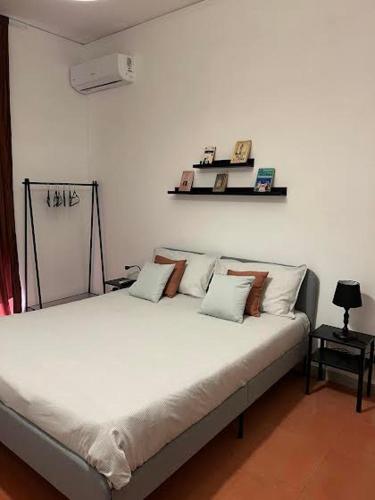 een wit bed met kussens in een kamer bij Casa Castagna Dependance Pisapia in Pontecagnano