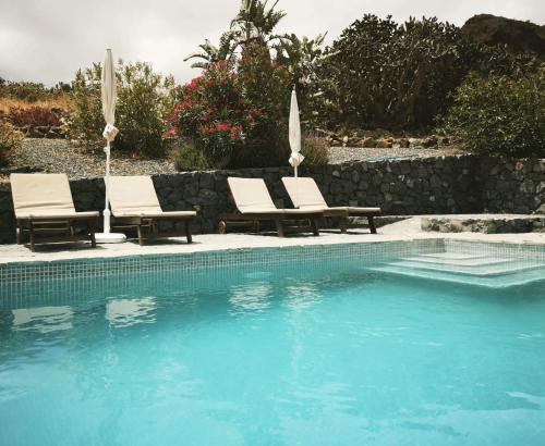 a swimming pool with two chairs and a pool at Viña Camello in Buenavista del Norte