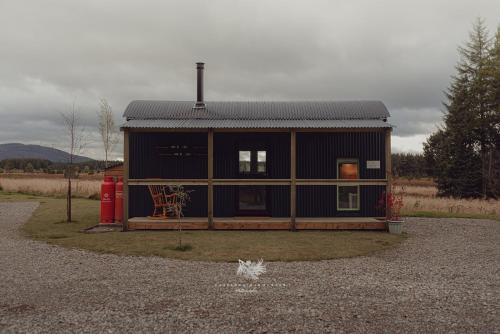 a small house in a gravel lot with a red fire hydrant at Highland Shepherd Huts in Nethy Bridge