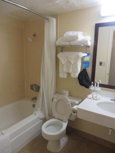 a bathroom with a toilet and a tub and a sink at Baymont by Wyndham Jefferson City in Jefferson City