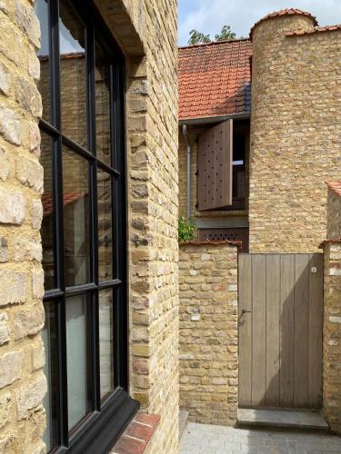 a brick house with a wooden door and a brick wall at Vis à Vis in Nieuwpoort