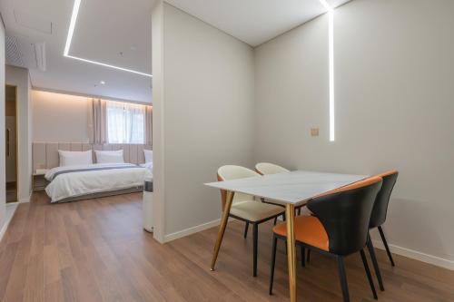a dining room with a table and chairs and a bedroom at Denbasta Central Hotel Seomyeon in Busan